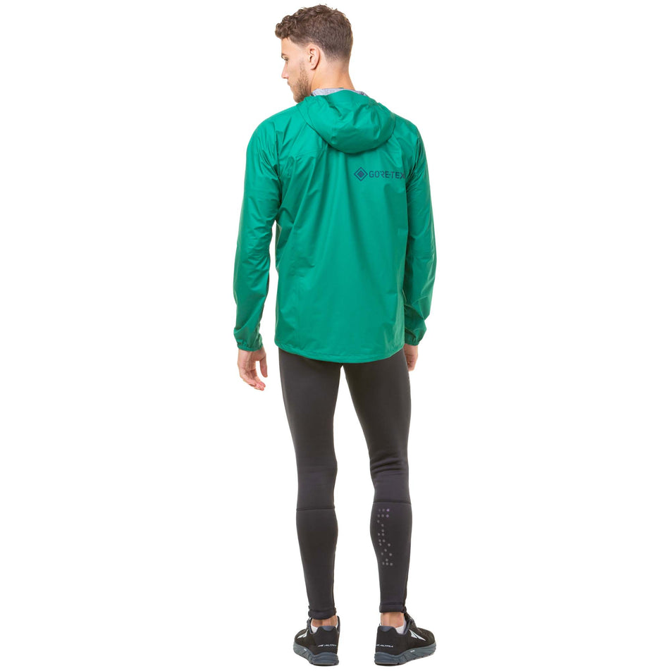Back view of a model wearing a Men's Tech GORE-TEX Mercurial Jacket in the Lawn/Deep Lagoon colourway. Model is also wearing Ronhill running tights and Altra running shoes. (8048099786914)