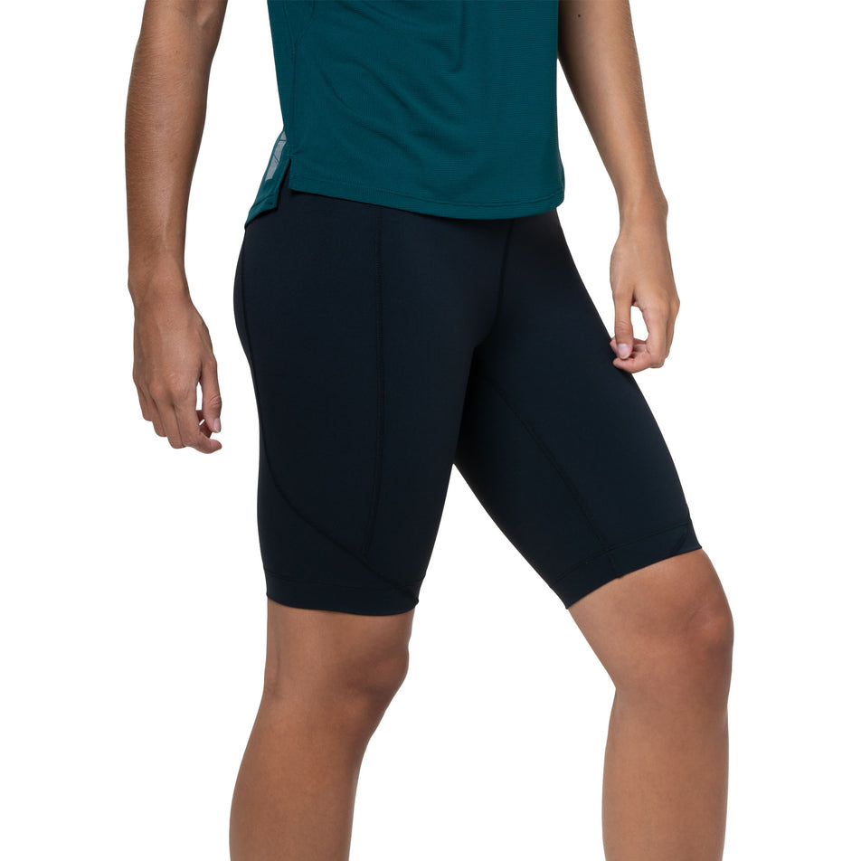 Angled view of a model wearing the Ronhill Women's Tech Stretch Short in the All Black colourway. (8583497482402)
