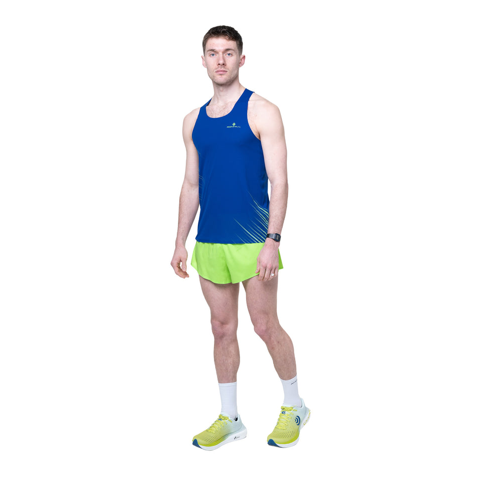 Front view of a model wearing the Ronhill Men's Tech Race Short in the Fluo Green/Dark Cobalt colourway.