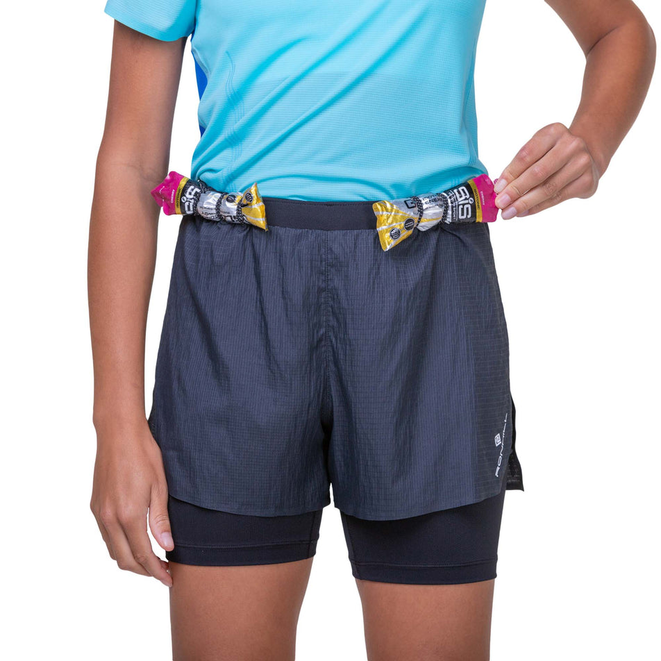 Front view of a model wearing the Ronhill Women's Tech Race Twin Short in the All Black colourway, and demonstrating that energy gels can be stored in the elasticated front loops. Model is also wearing a running top. (8158813323426)