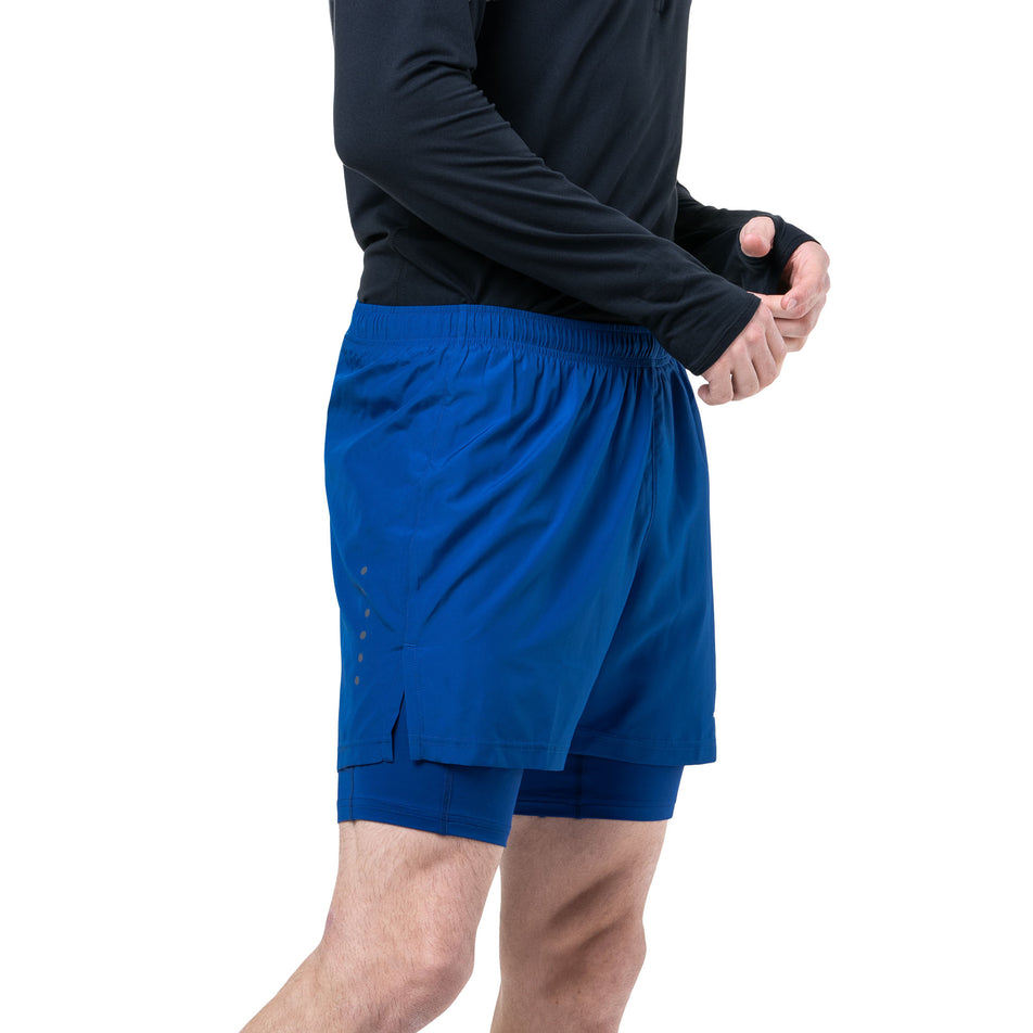 Side view of a model wearing the Ronhill Men's Core Twin Short in the Dark Cobalt/Bright White colourway. (8748846284962)