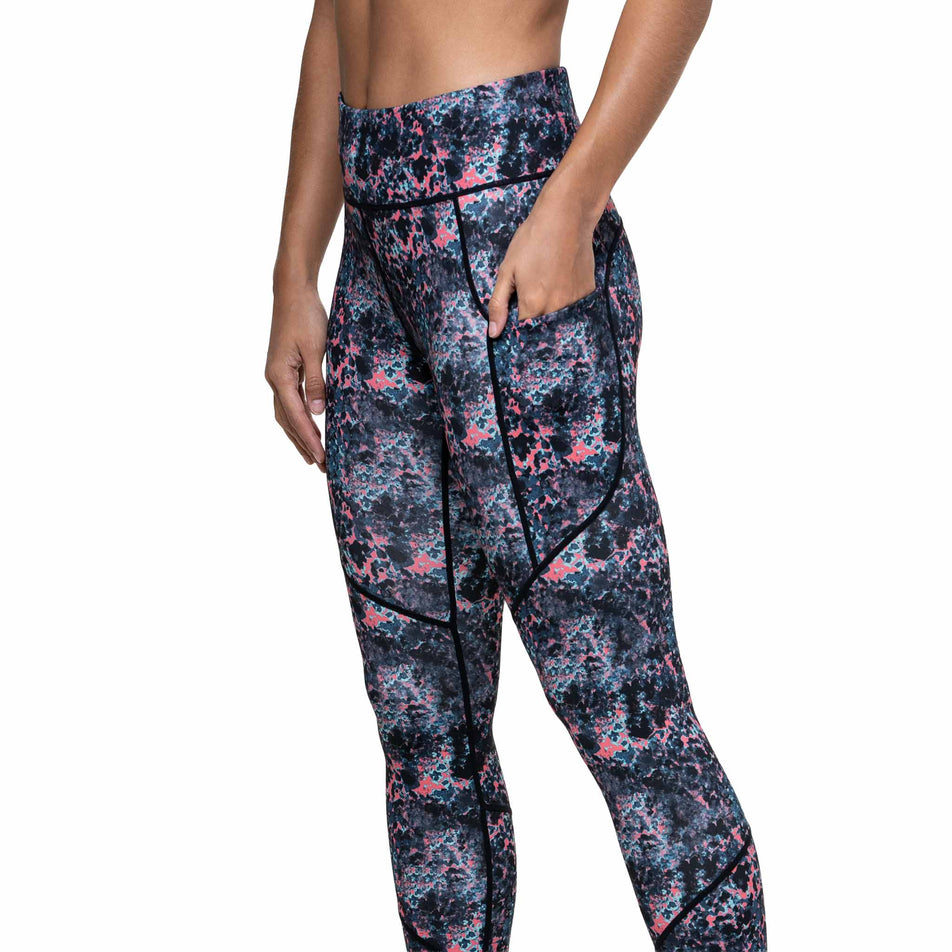 Angled view of a model wearing the Ronhill Women's Tech Tight in the Coralescent colourway. (8747577770146)