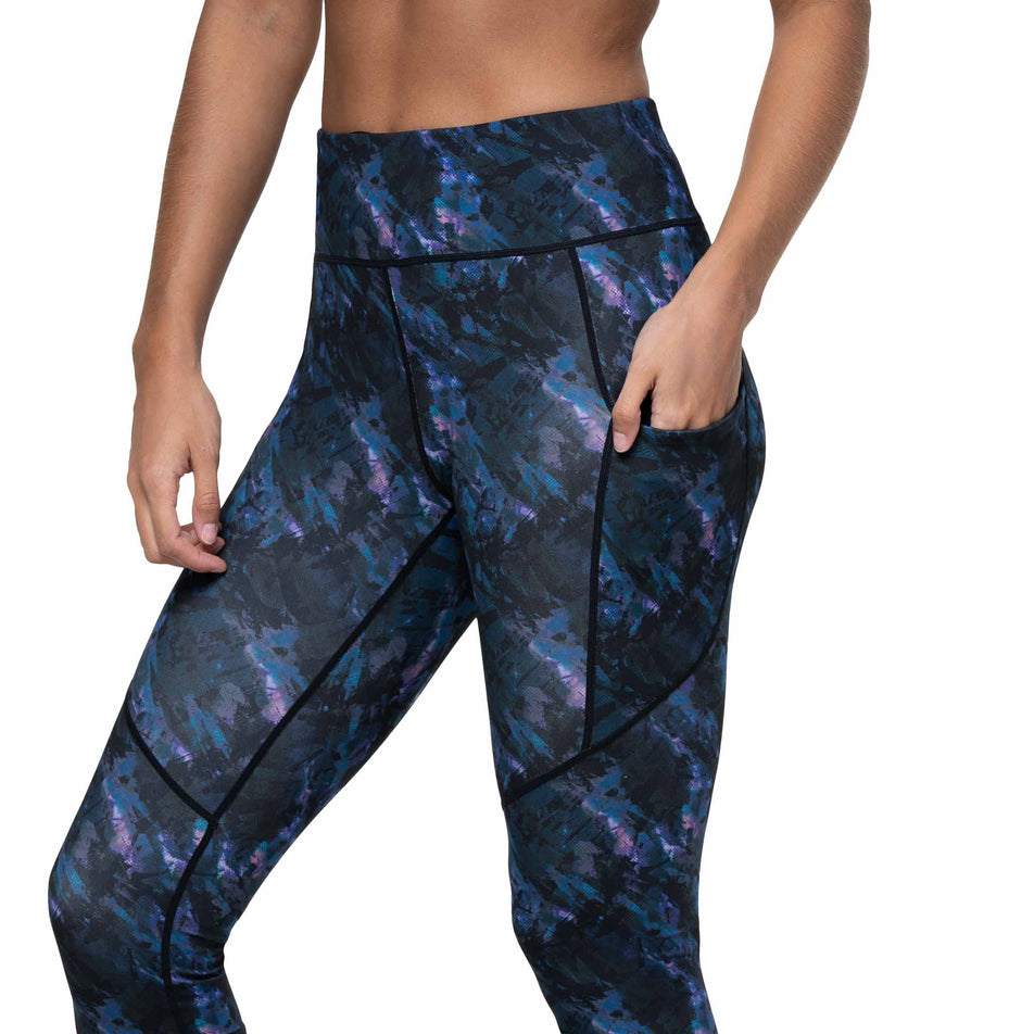 A model demonstrating the drop-in stash pocket on the side of the Ronhill Women's Tech Tight in the Cosmic colourway. (8747579211938)