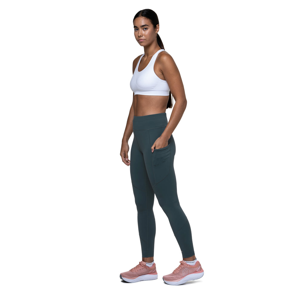 A model demonstrating the drop-in pocket on the side of the Ronhill Women's Tech Tight in the Evening Haze colourway. (8742711853218)