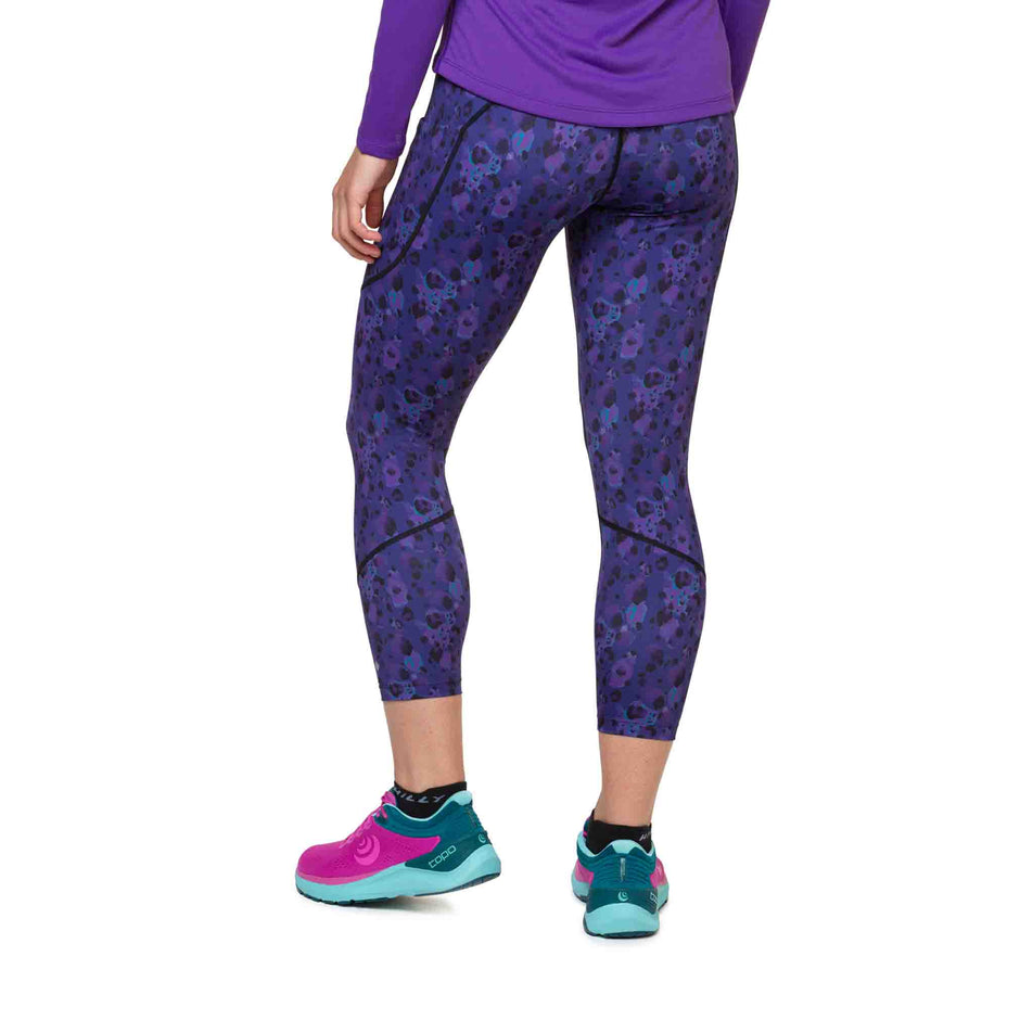 Back view of a model wearing the Ronhill Women's Tech Crop Tight in the Purple Leopard colourway. Model is also wearing shoes and a top. (8490052518050)