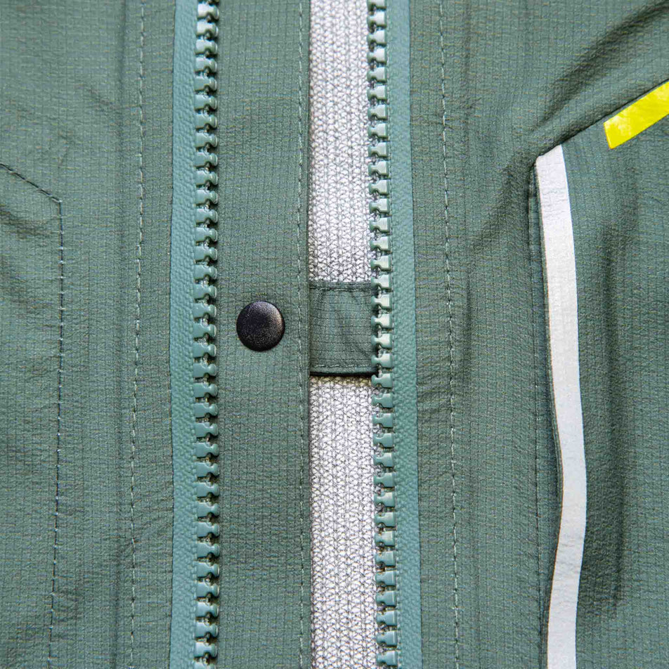 A model demonstrating the chest clip that can be used to connect the front left-side and right-side of a Ronhill Men's Tech Fortify Jacket when it is unzipped. Jacket is being worn by a model. (8470624895138)