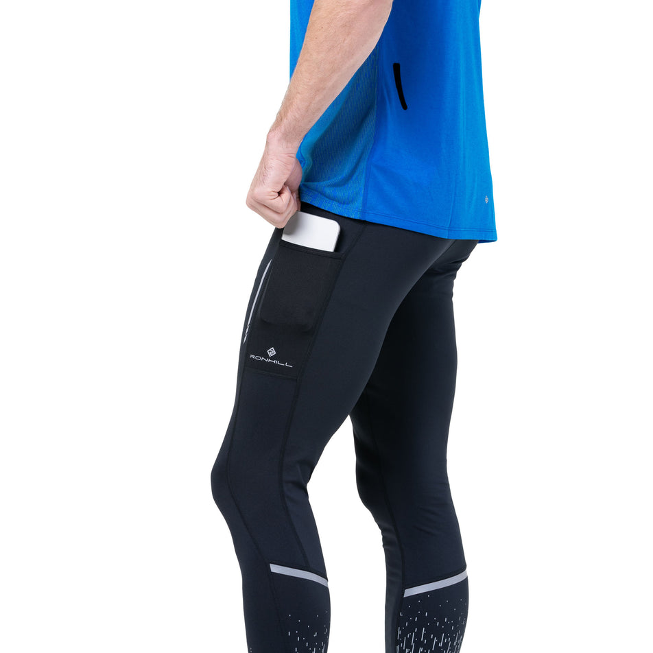 Side view of a model wearing the Ronhill Men's Tech Reflect S/S Tee in the ElecBlueMarl/Reflect colourway. (8747641831586)