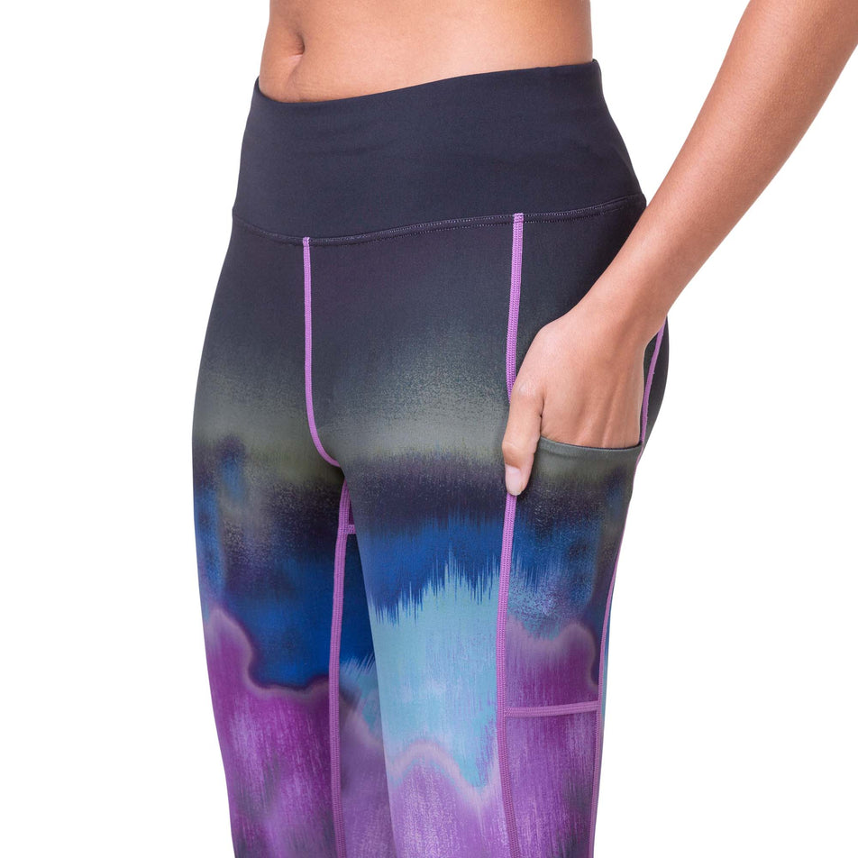 A model wearing the Ronhill Women's Tech Gradient Crop Tight, and highlighting the stretch pocket on the outside of the left thigh. (8160844742818)