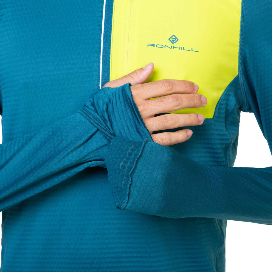 A model demonstrating the integrated mittens and hand covers at the end of a Ronhill Men's Tech Winter 1/2 Zip's sleeves. (8490256990370)