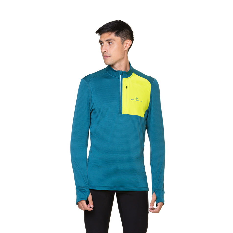 Front view of a model wearing a Ronhill Men's Tech Winter 1/2 Zip in the Deep Teal/Acid colourway. Model is also wearing leggings. (8490256990370)