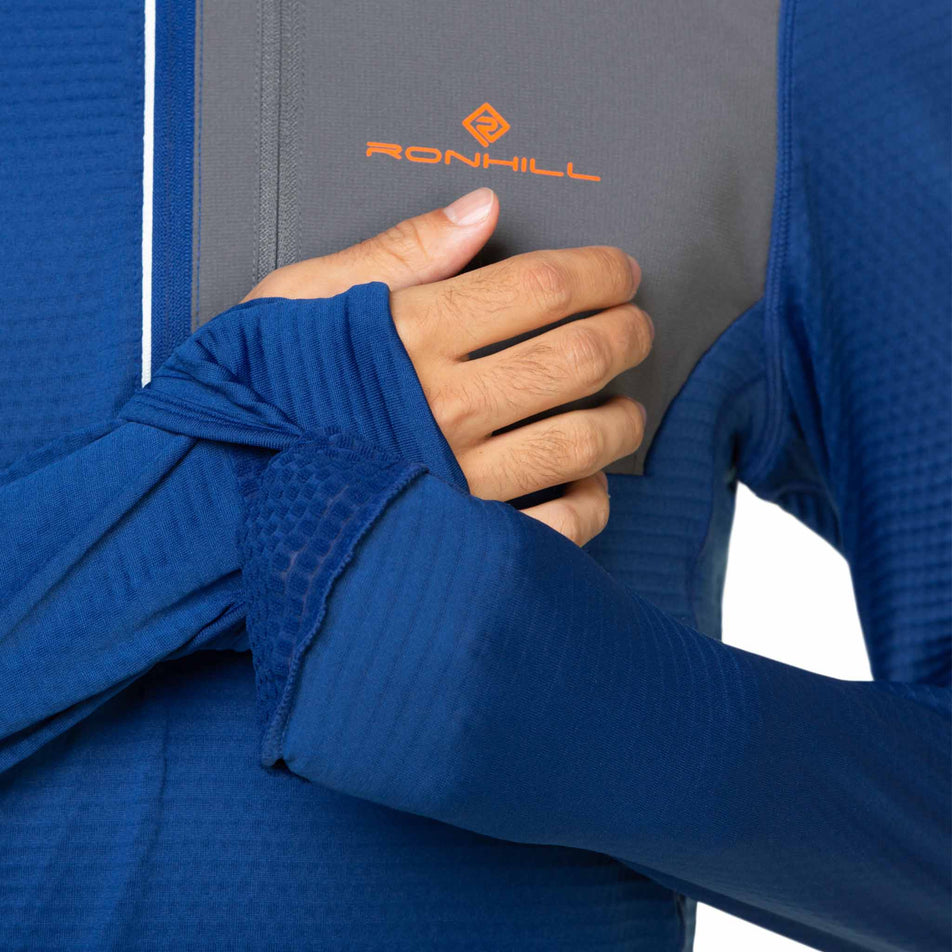 A model highlighting the integrated wrists and hand covers on the Ronhill Men's Tech Winter 1/2 Zip. Model is wearing the top. (8491275387042)