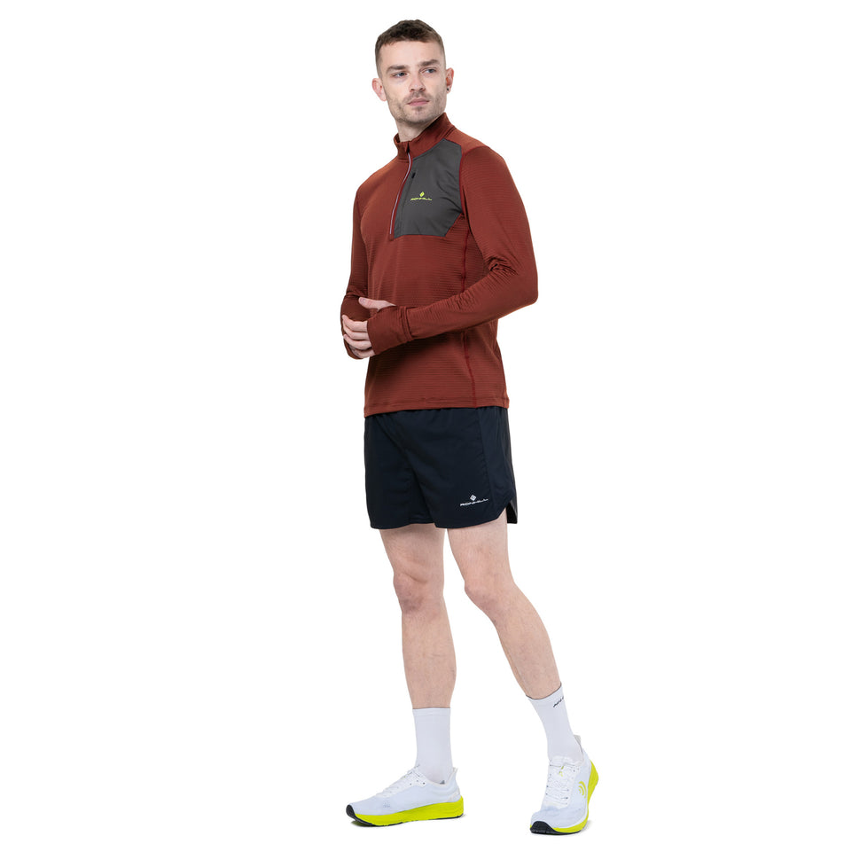 Angled view of a model wearing the Ronhill Men's Tech Winter 1/2 Zip in the Chestnut/Oxide colourway. (8747100700834)