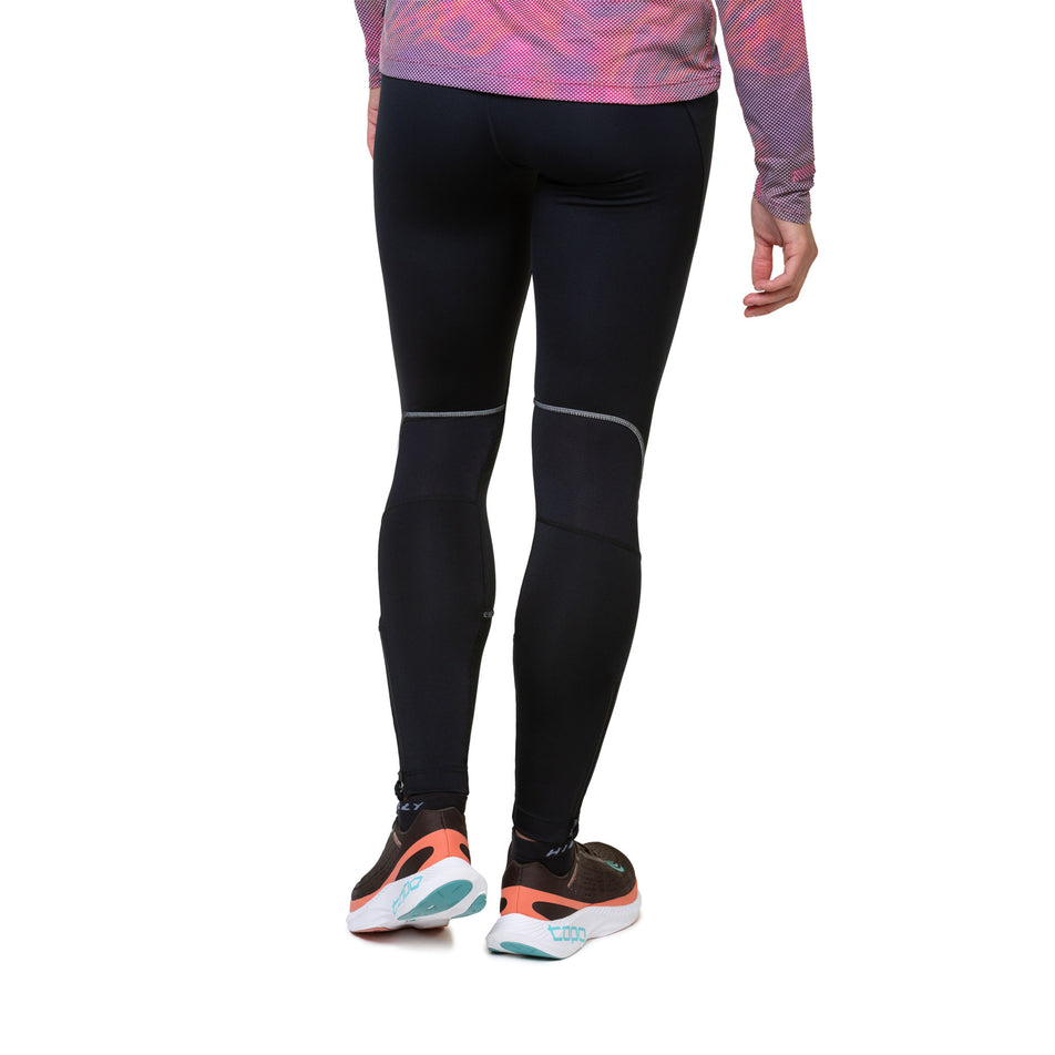 Back view of a model wearing the Ronhill Women's Tech Paragon Tight in the All Black colourway. Model is also wearing shoes and a top. (8489936912546)