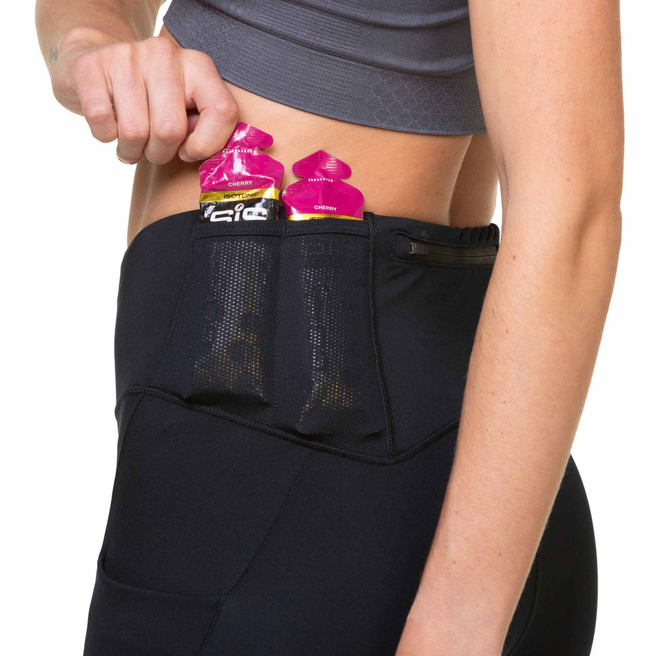 A model demonstrating that energy gels can be stored the Ronhill Women's Tech Paragon Tights' waistband pockets. (8489936912546)