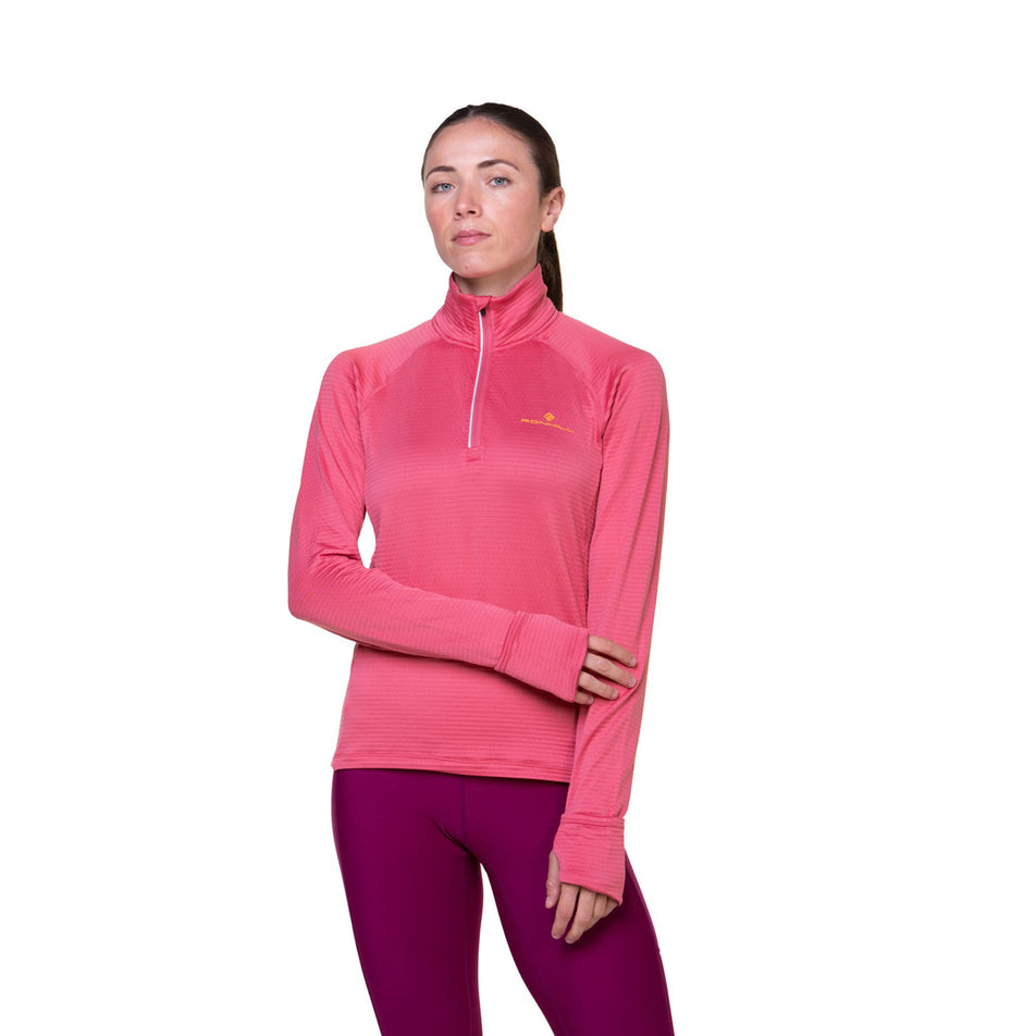 Front view of a model wearing the Ronhill Women's Tech Winter 1/2 Zip in the Salsa/Mango colourway. Model is also wearing leggings. (8491142414498)