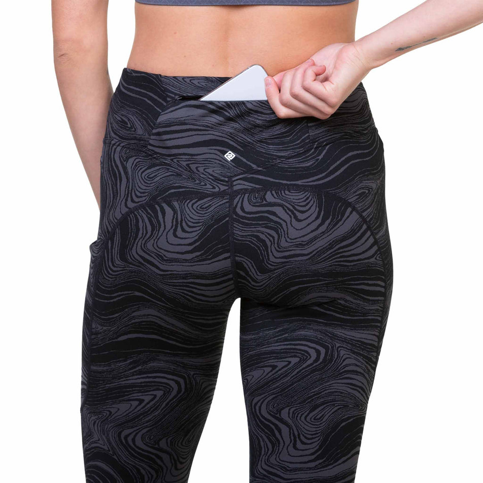 A model demonstrating the zipped back pocket on the Ronhill Women's Tech Deluxe Tight. The tights are being worn by a model. (8469451112610)