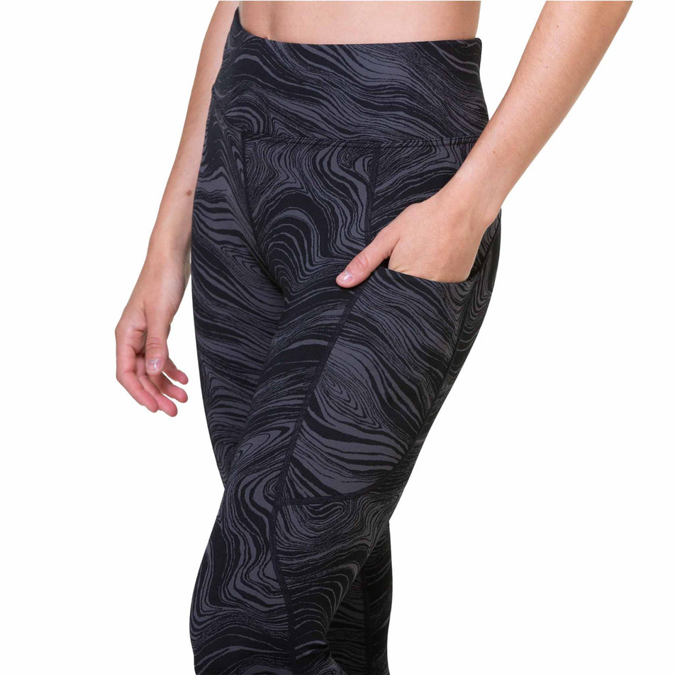 A model demonstrating the stretch side pocket on the outside of the left-leg of the Ronhill Women's Tech Deluxe Tight. The tights are being worn by a model. (8469451112610)