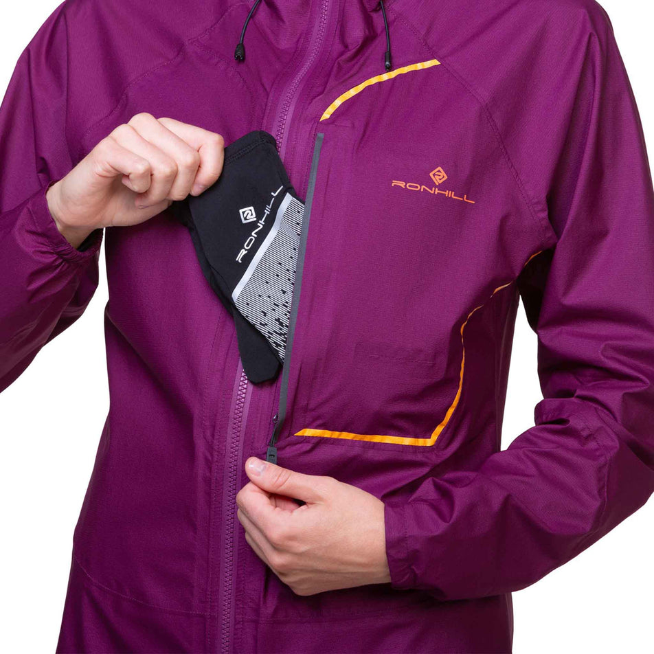 A model demonstrating that gloves can be stored in the chest pocket of a Ronhill Women's Tech Fortify Jacket. Jacket is being worn by a model. (8469350121634)