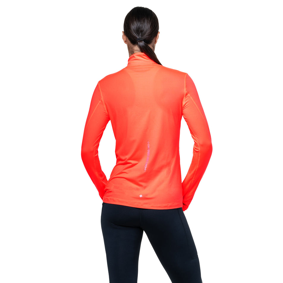 Back view of a model wearing the Ronhill Women's Tech Reflect 1/2 Zip in the Hot Coral/Reflect colourway. (8742195691682)
