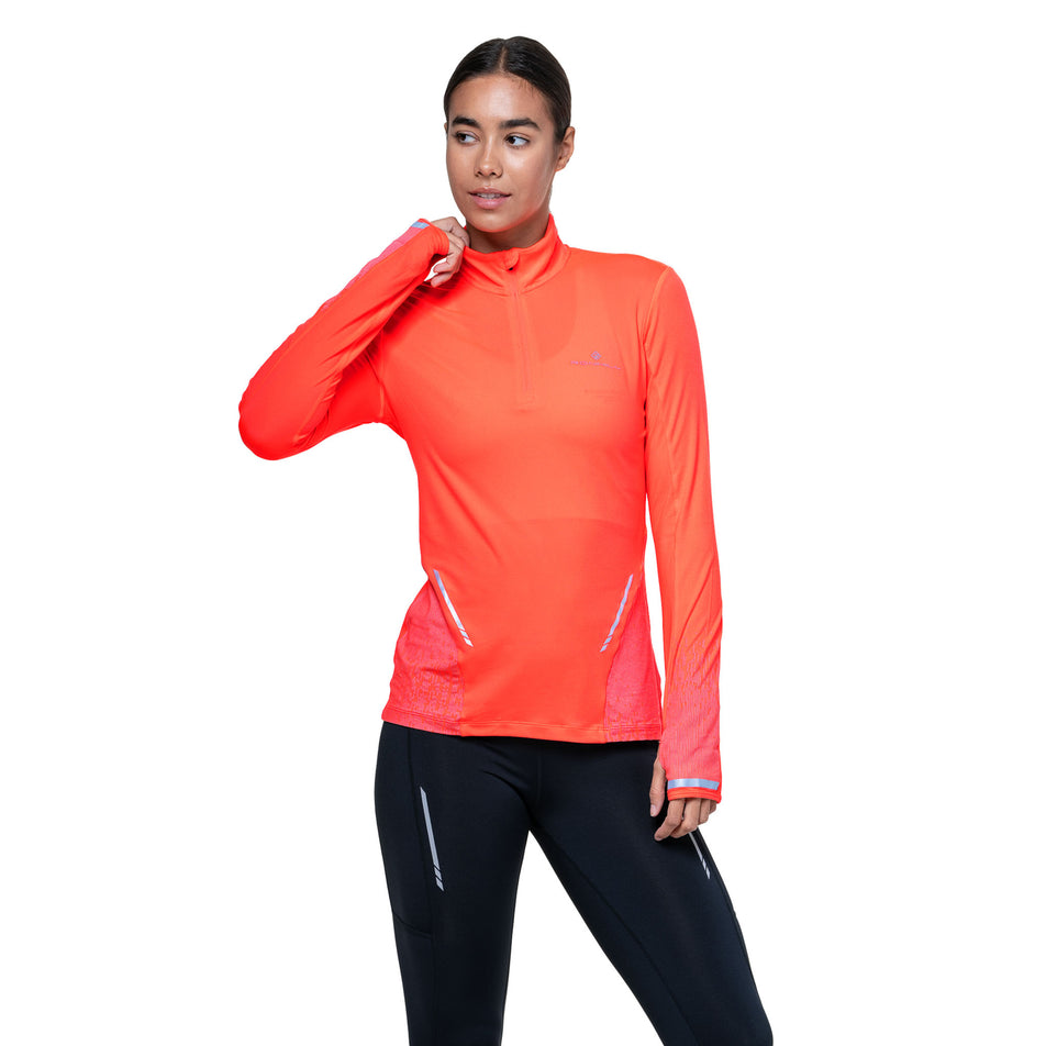 Front view of a model wearing the Ronhill Women's Tech Reflect 1/2 Zip in the Hot Coral/Reflect colourway. (8742195691682)