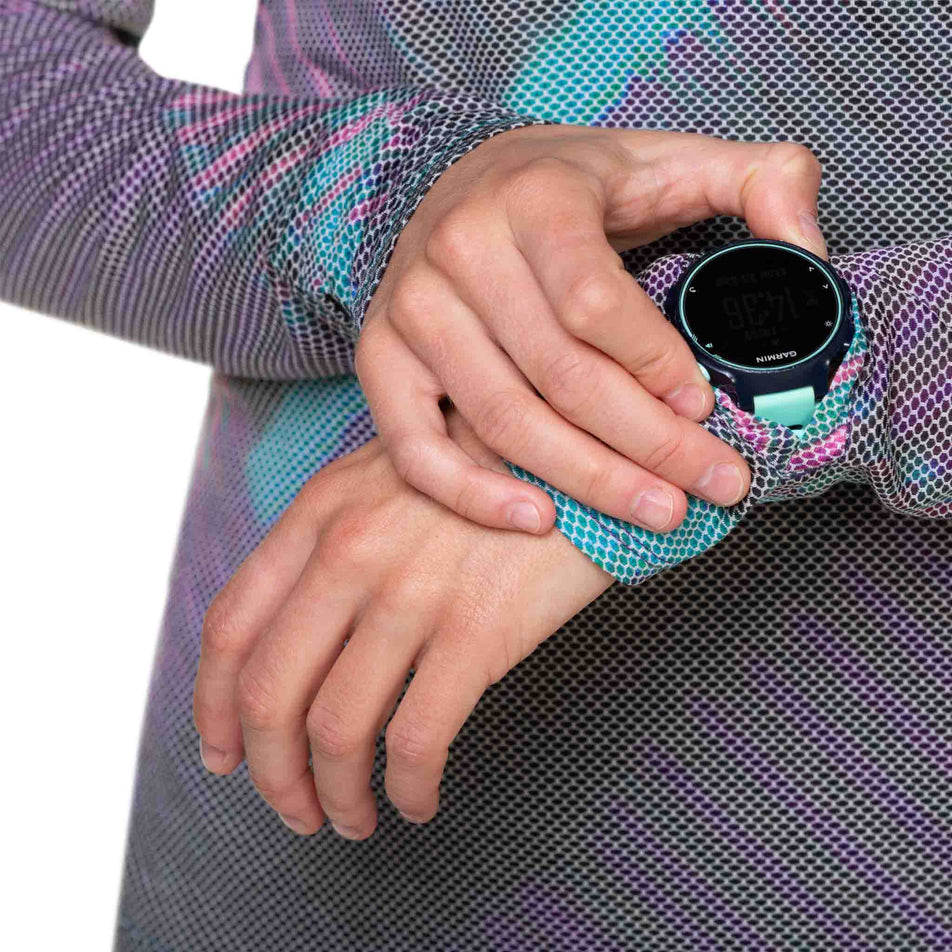 A model demonstrating that a running watch screen will fit through the gap in the fabric at the left-wrist of the Ronhill Women's Tech Golden Hour L/S Tee. (8490067361954)
