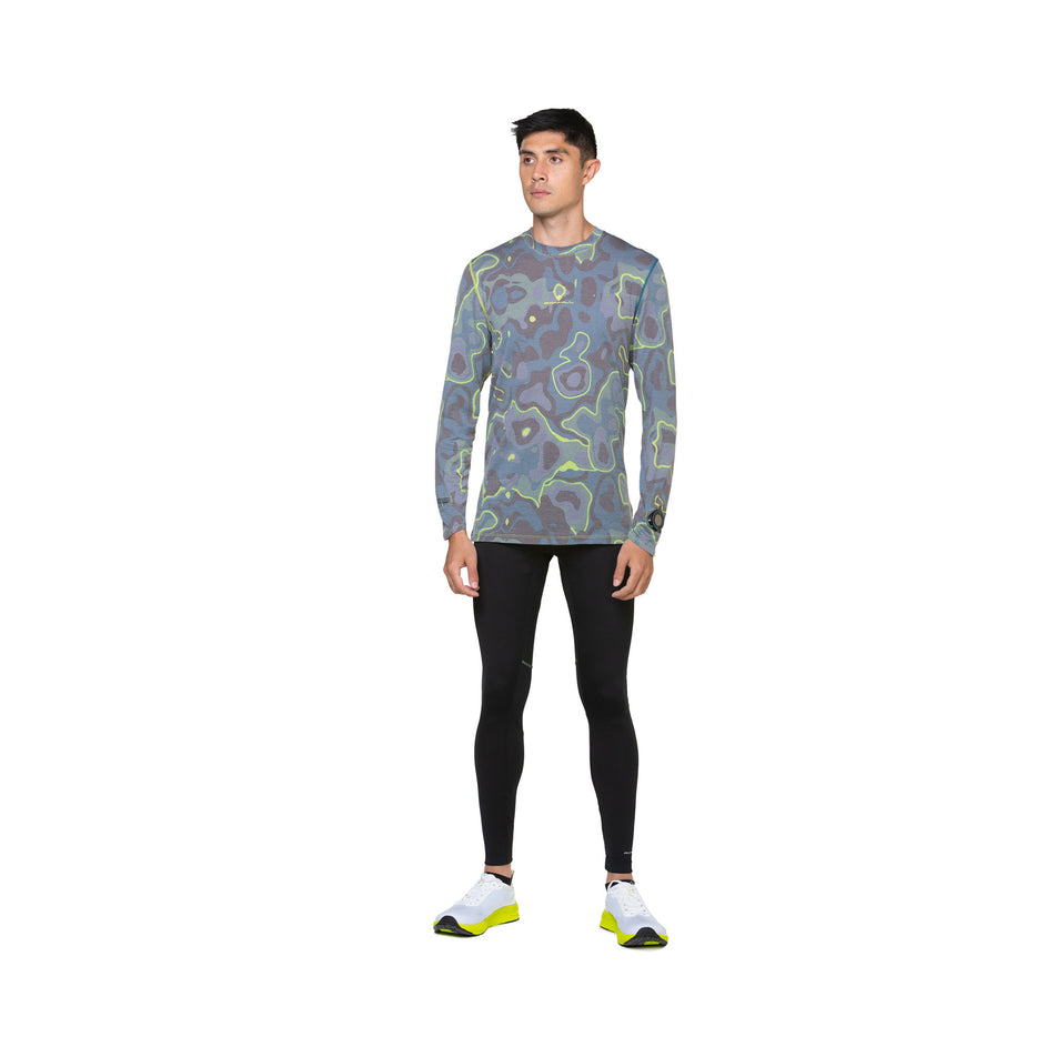Front view of a model wearing the Ronhill Men's Tech Golden Hour L/S Tee in the Deep Teal Heat Map colourway. Model is also wearing leggings and shoes. (8490280550562)