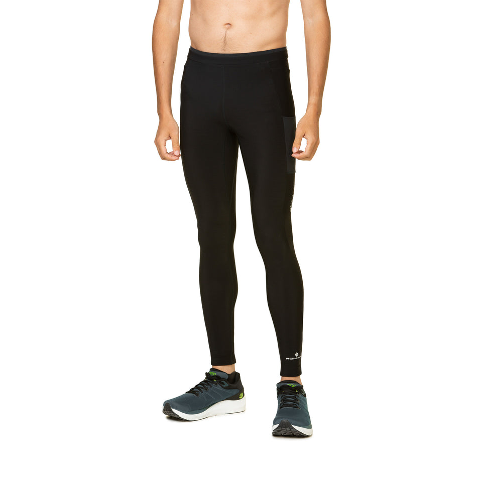 Front view of a model wearing the Ronhill Men's Tech Winter Tight in the All Black colourway. Model is also wearing shoes. (8491238686882)