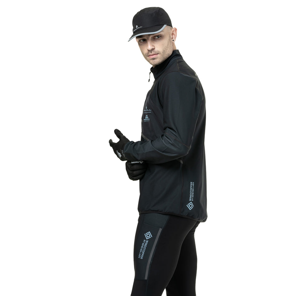 Side view of a model wearing the Ronhill Men's Tech GORE-TEX Windstopper Jacket in the All Black colourway. (8782555185314)