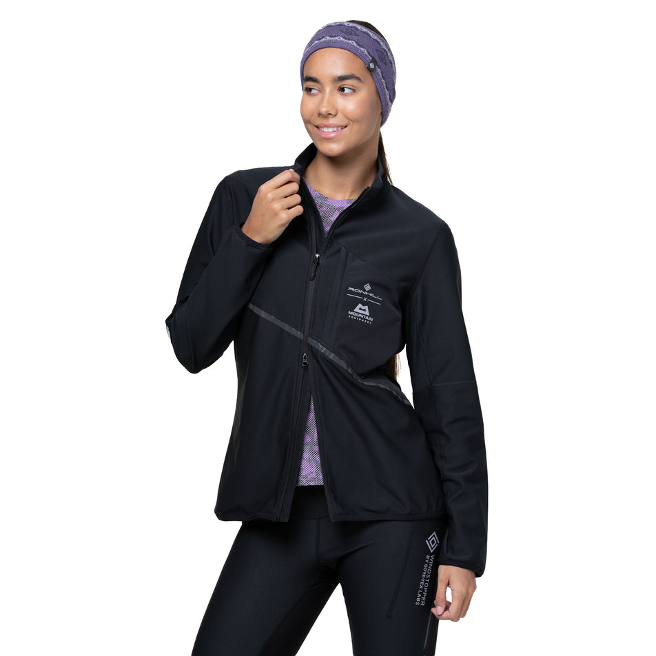 A model demonstrating the open-end zip on the Ronhill Women's Tech GORE-TEX Windstopper Jacket in the All Black colourway. (8742206898338)