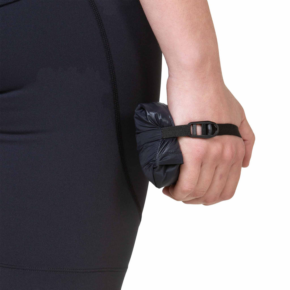 A model holding a folded up Ronhill Women's Tech All-Terrain Jacket in the All Black colourway. (8563593511074)