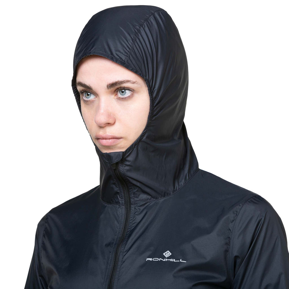 Front view of a model wearing the Ronhill Women's Tech All-Terrain Jacket in the All Black colourway with the hood up. (8563593511074)