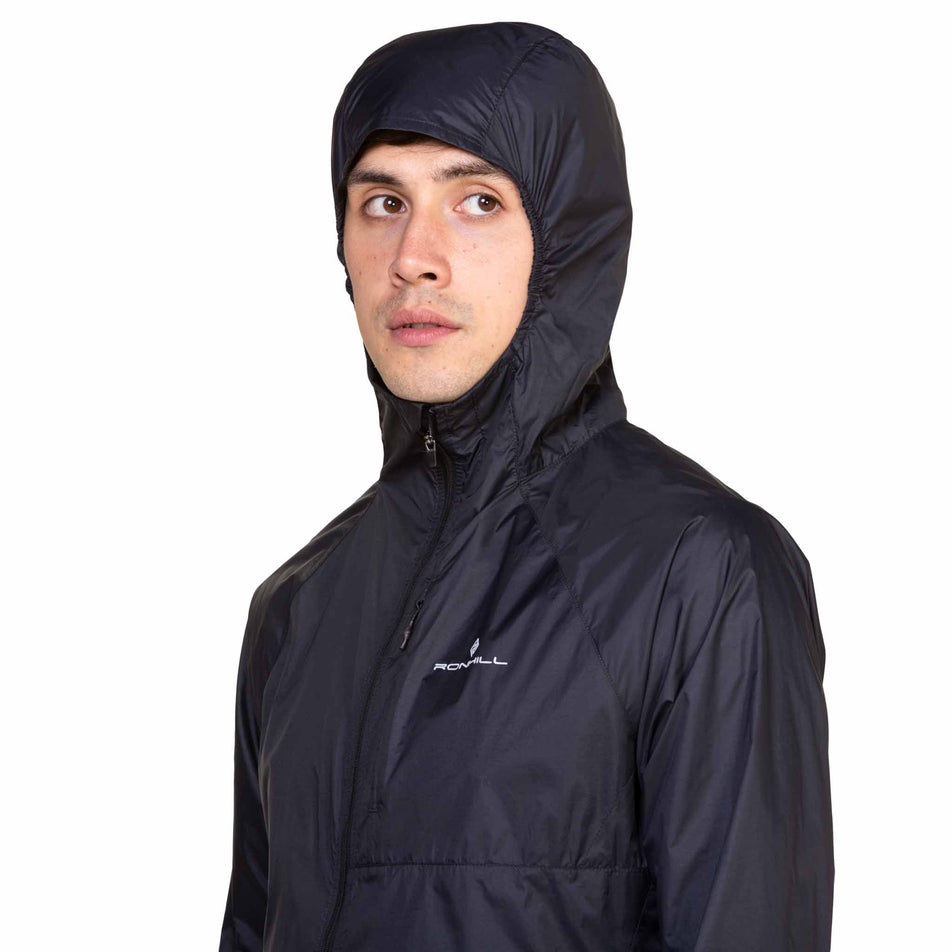 Front view of a model wearing the Ronhill Men's Tech All-Terrain Jacket in the All Black colourway with the hood up. (8563617431714)