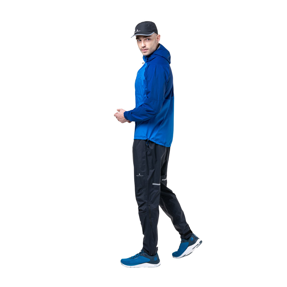 Side view of a model wearing the Ronhill Men's Tech Storm Jacket in the Ocean/Electric Blue colourway. (8742825853090)