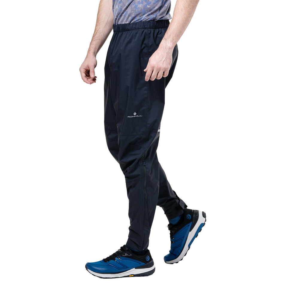 Side view of a model wearing the Ronhill Unisex Tech Storm Pant in the All Black colourway. (8748339593378)