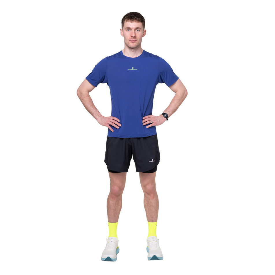 Front view of a model wearing the Ronhill Men's Tech S/S Tee in the Dark Cobalt/Fluo Green colourway.
