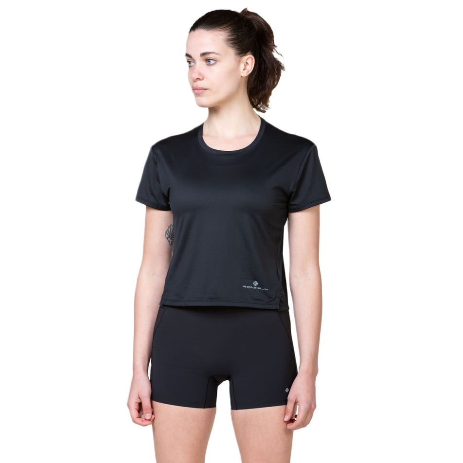 Front view a model wearing a Ronhill Women's Tech Breathe S/S Tee in the All Black colourway. (8581016780962)