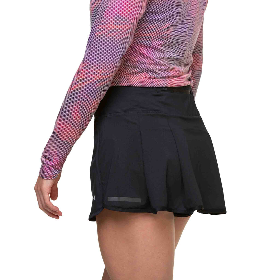 Angled view of a model wearing the Ronhill Women's Tech Skort in the All Black colourway. (8581024678050)