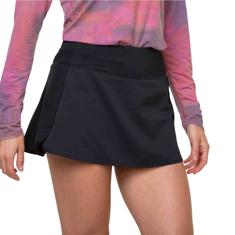 Front view of a model wearing the Ronhill Women's Tech Skort in the All Black colourway. (8581024678050)