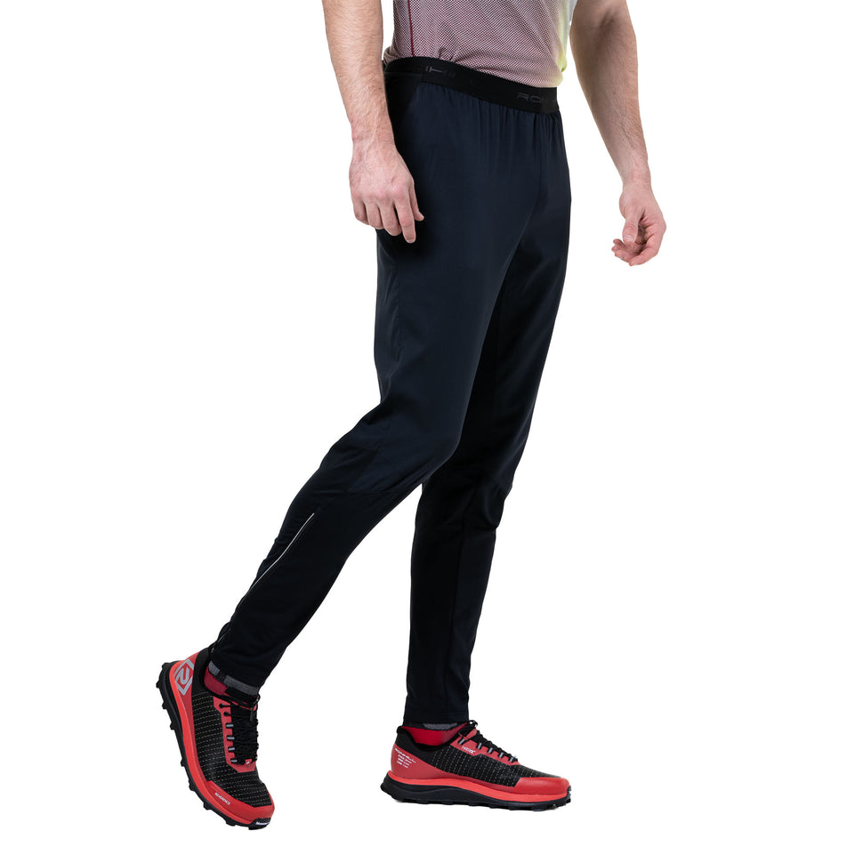 Side view of a model wearing the Ronhill Men's Tech All-Terrain Trackster in the All Black colourway. (8742887096482)