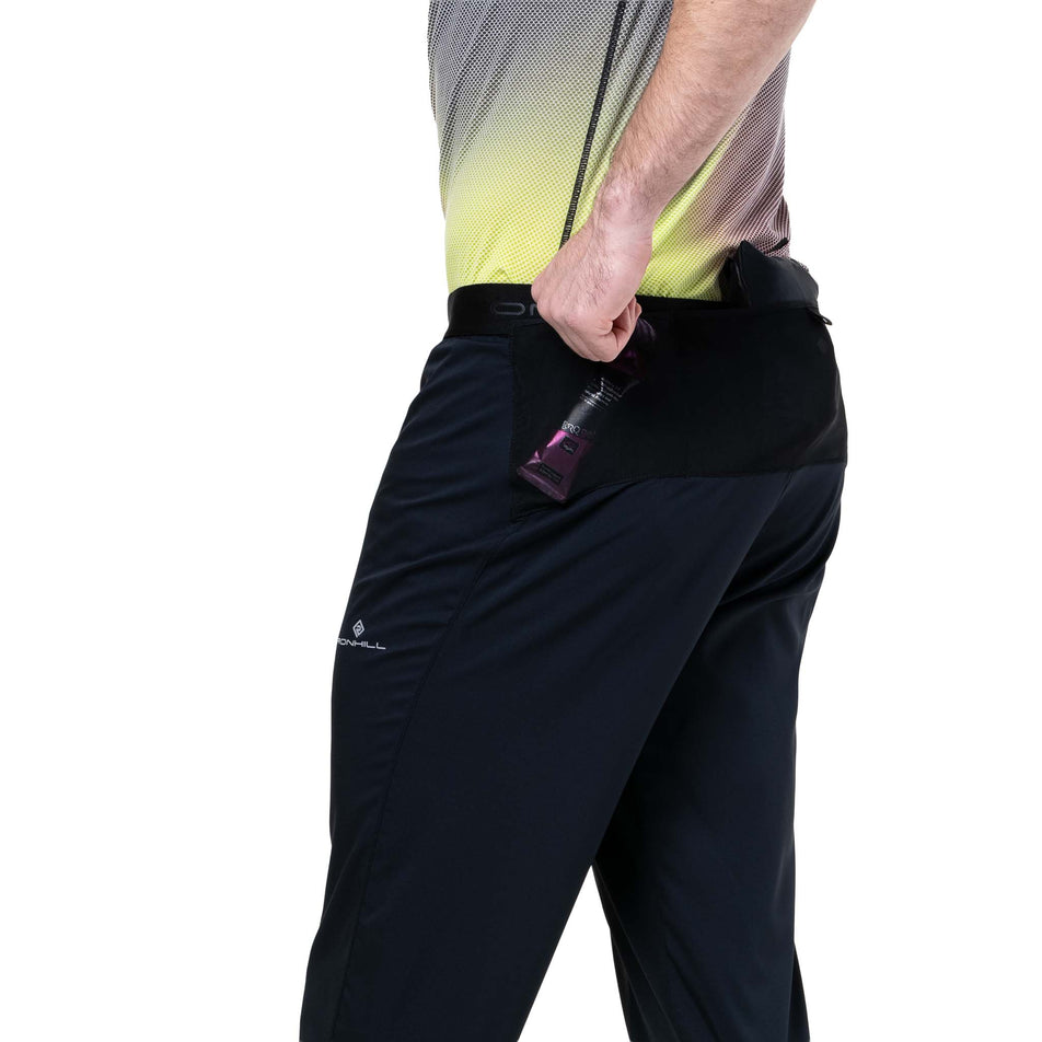 A model demonstrating the drop-in storage on the Ronhill Men's Tech All-Terrain Trackster in the All Black colourway. (8742887096482)