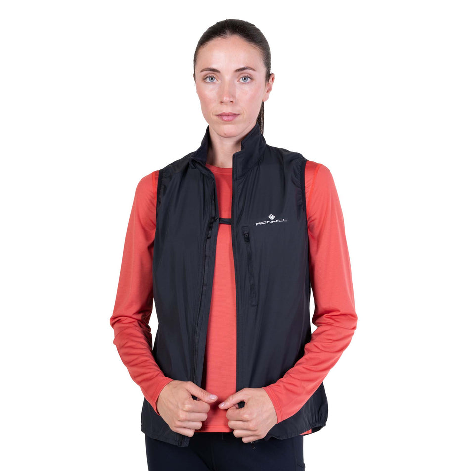 Front view of a model wearing the Ronhill Women's Core Gilet in the Black/Bright White colourway demonstrating the chest clip.