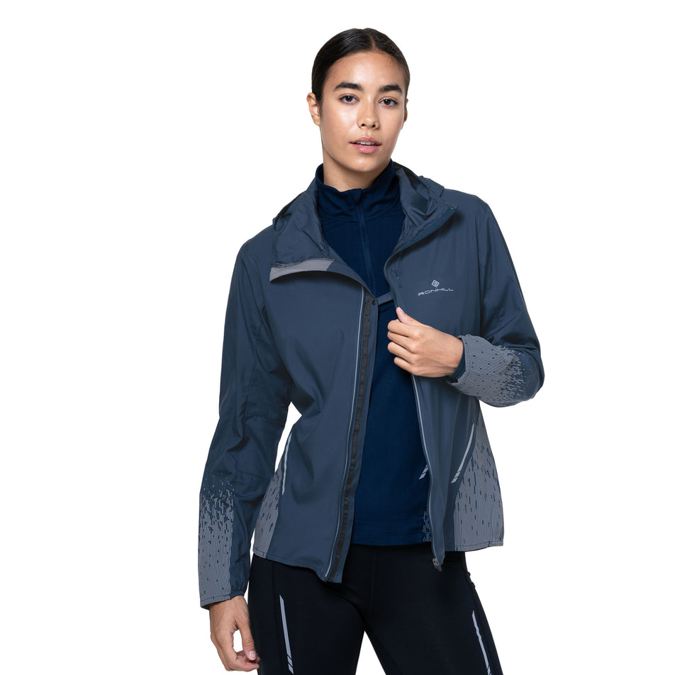 Front view of a model wearing the Ronhill Women's Tech Reflect Jacket in the Dark Navy/Reflect colourway. (8747149787298)