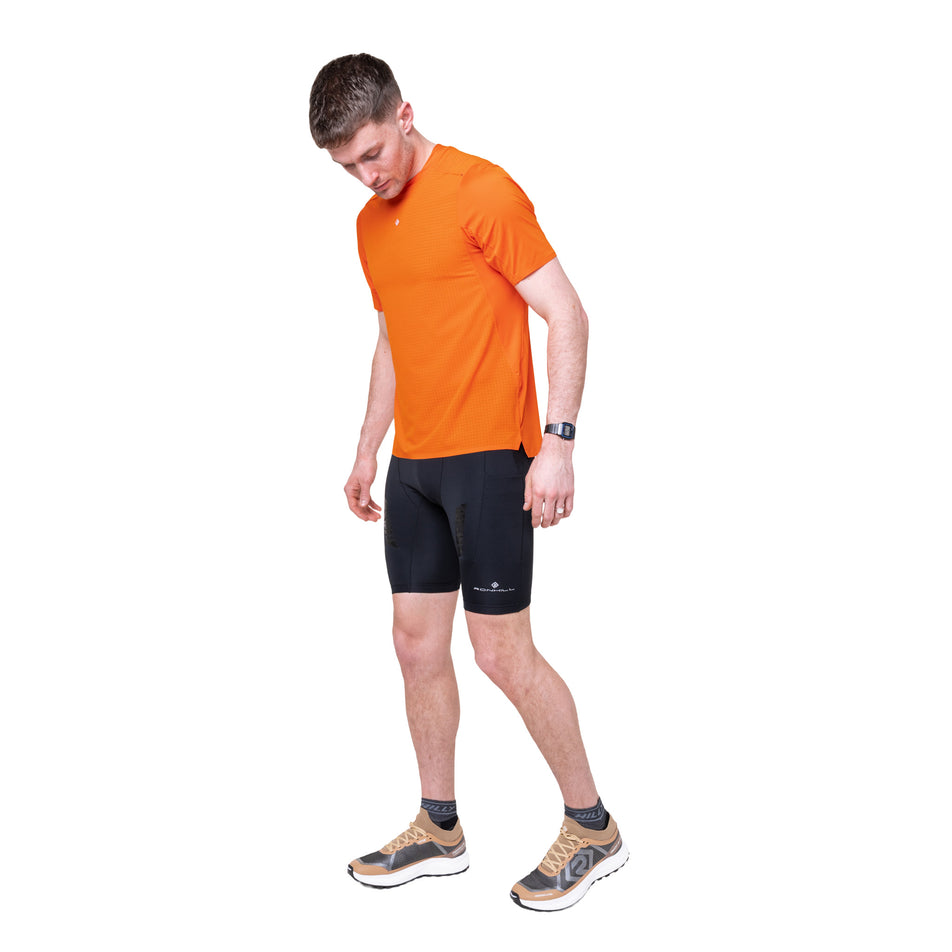 Angled view of a model wearing the Ronhill Men's Tech All-Terrain S/S Tee in the Ronhill Red colourway.