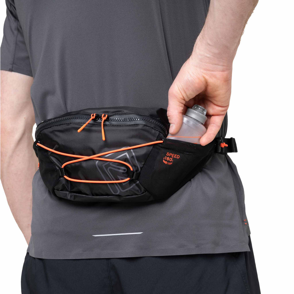 A model demonstrating storing a small soft flask in the Ronhill Unisex Speed 180 in the Black/Ronhill Red colourway.