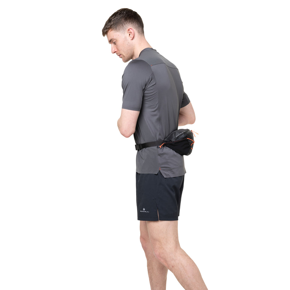 Side view of a model wearing the Ronhill Unisex Speed 180 in the Black/Ronhill Red colourway.