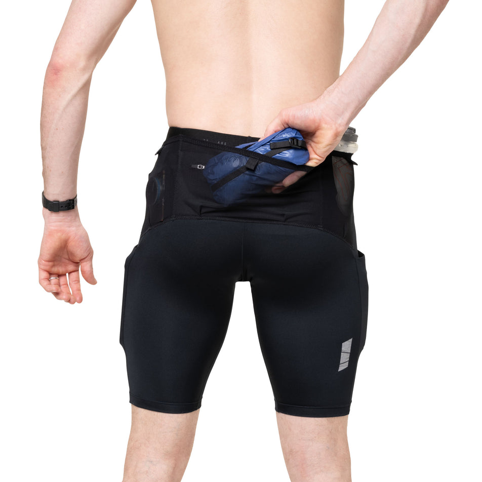 A model demonstrating the stash pocket on the back of the Ronhill Men's Tech All-Terrain 10