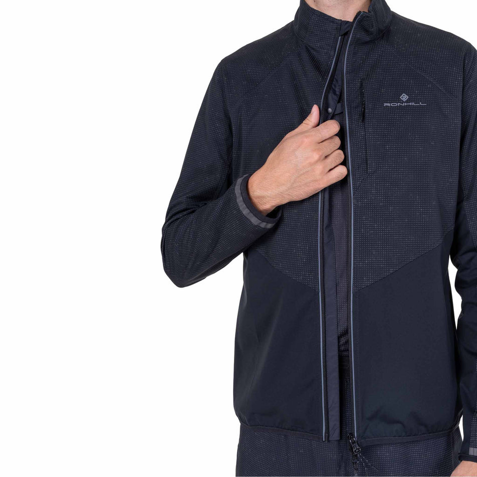 Front view of a model wearing the Ronhill Men's Tech Reflect Lux Jacket in the Black/Reflect colourway.