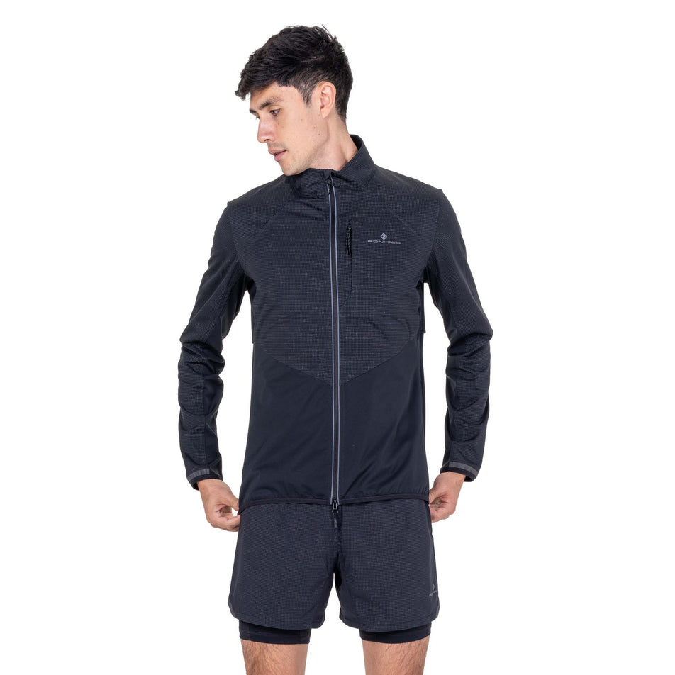 Front view of a model wearing the Ronhill Men's Tech Reflect Lux Jacket in the Black/Reflect colourway.