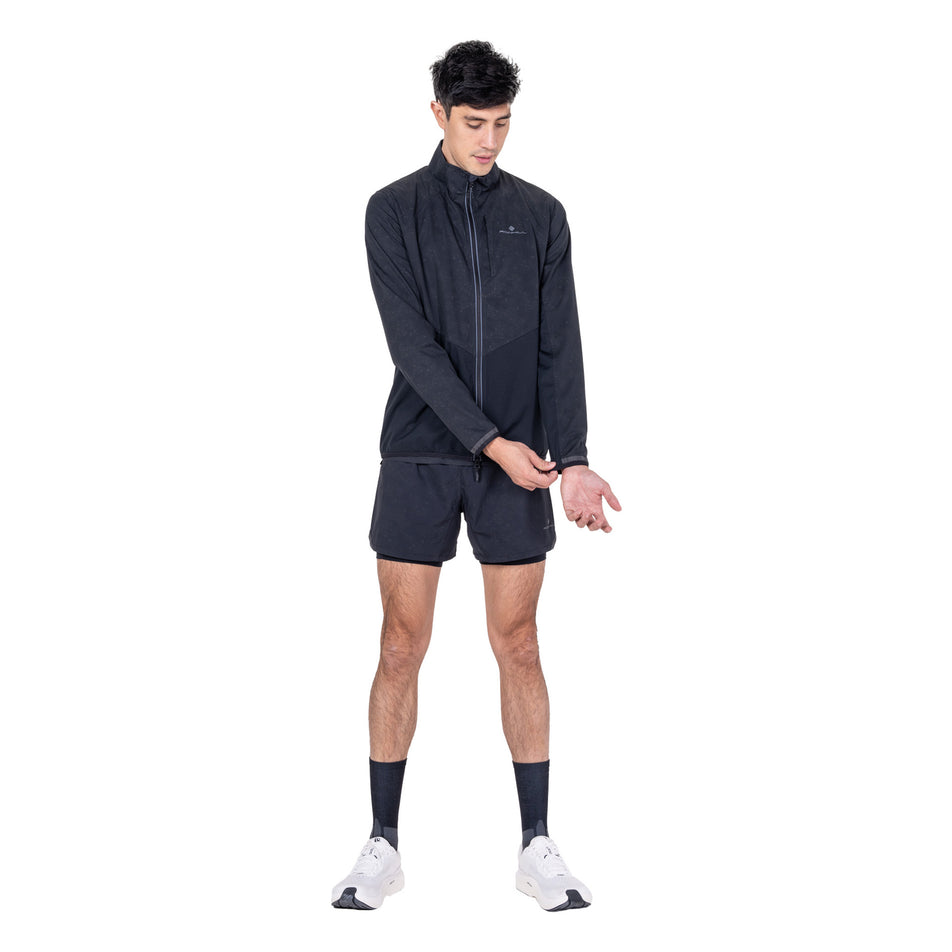 Front view of a model wearing the Ronhill Men's Tech Reflect Lux Jacket in the Black/Reflect colourway.