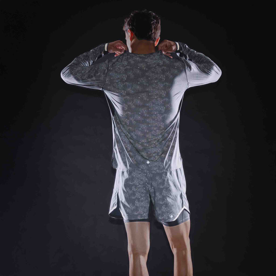 Back view of a model wearing the Ronhill Men's Tech Reflect Lux L/S Tee in the Black/Reflect colourway.